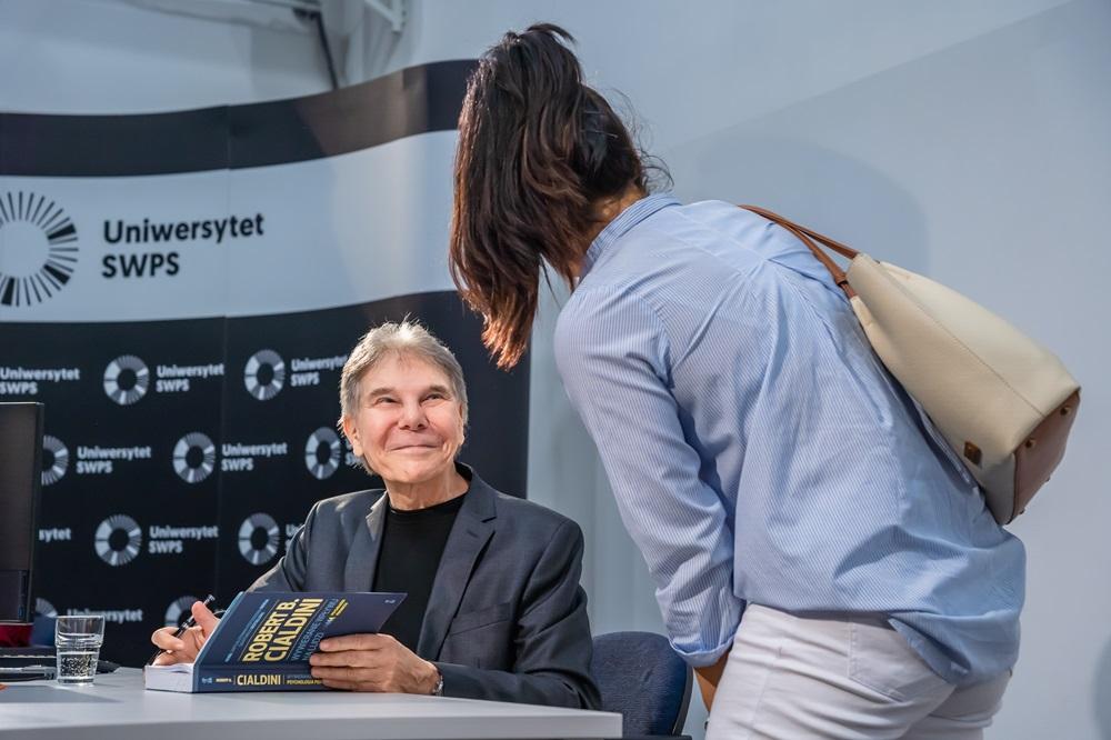 Wizyta profesora Cialdiniego na Uniwersytecie SWPS. Profesor Cialdini składa autograf