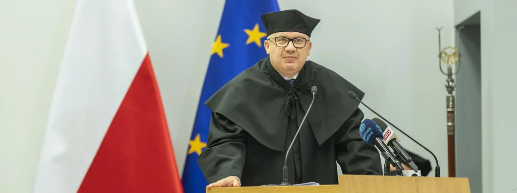 Profesor Adam Bodnar wygłasza wykład. W tle flaga Polski oraz flaga Unii Europejskiej