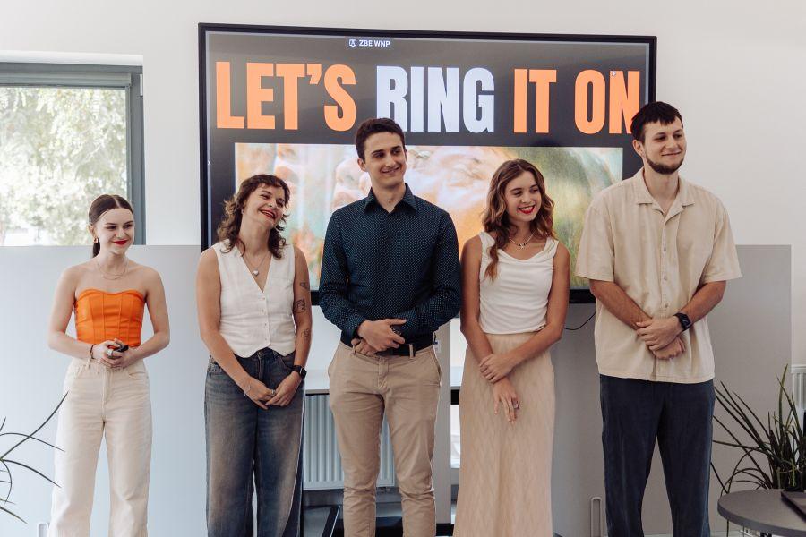 Pięcioro członków zespołu RingOn na tle slajdu z napisem „LET'S RING IT ON”