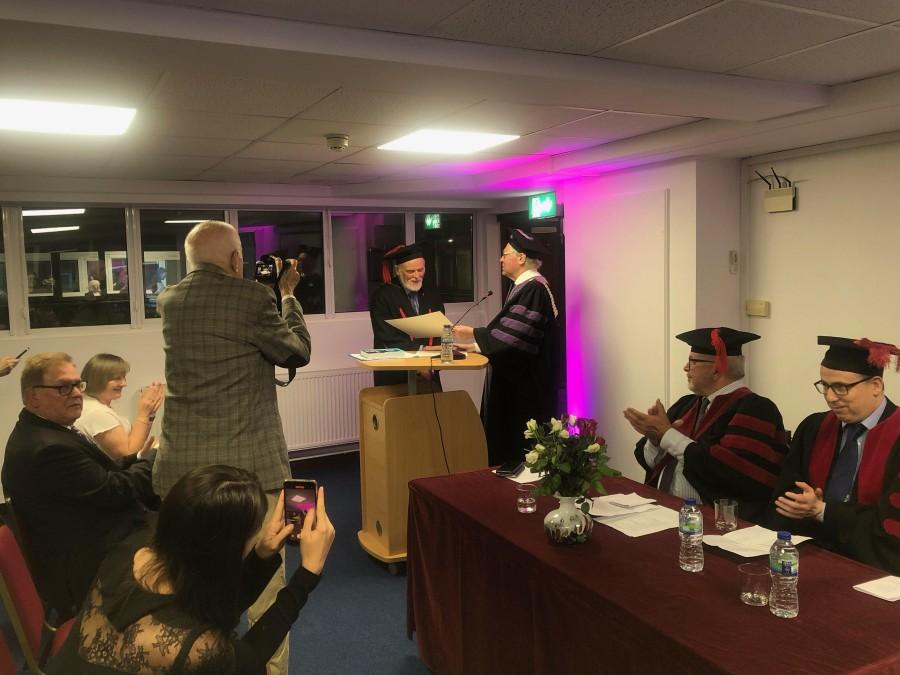 Profesor doktor habilitowany Paweł Boski odbiera dyplom doktora honoris causa. Uczestnicy uroczystości biją brawo i robią zdjęcia