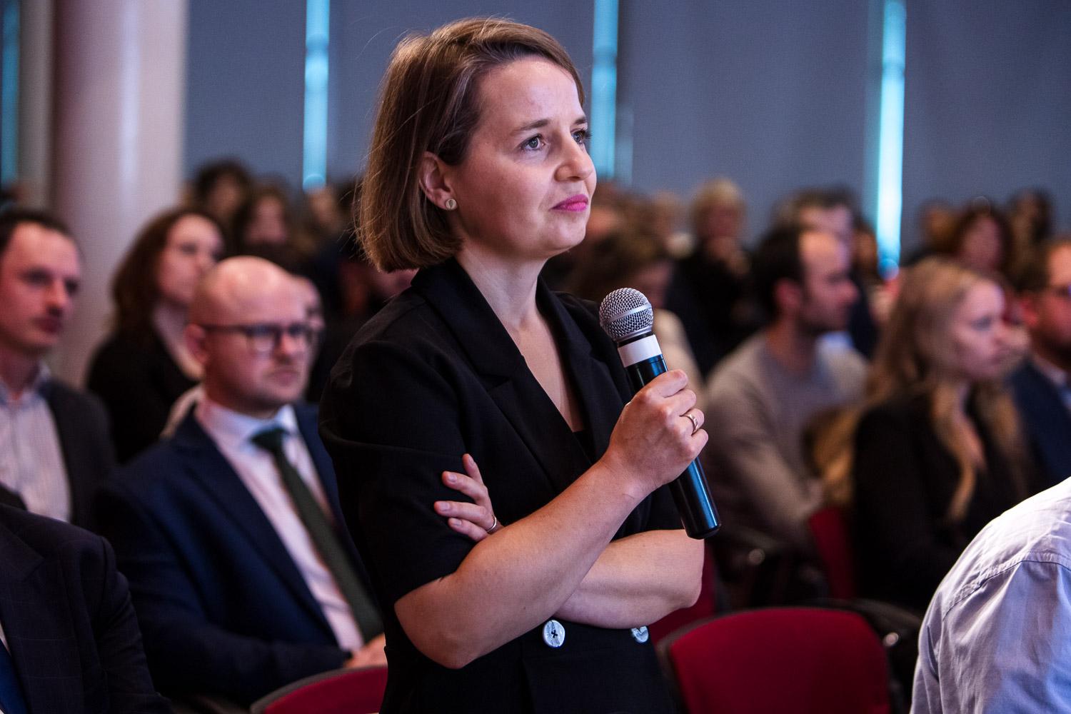 Doktor Justyna Kajta z mikrofonem, w tle siedzą uczestnicy gali