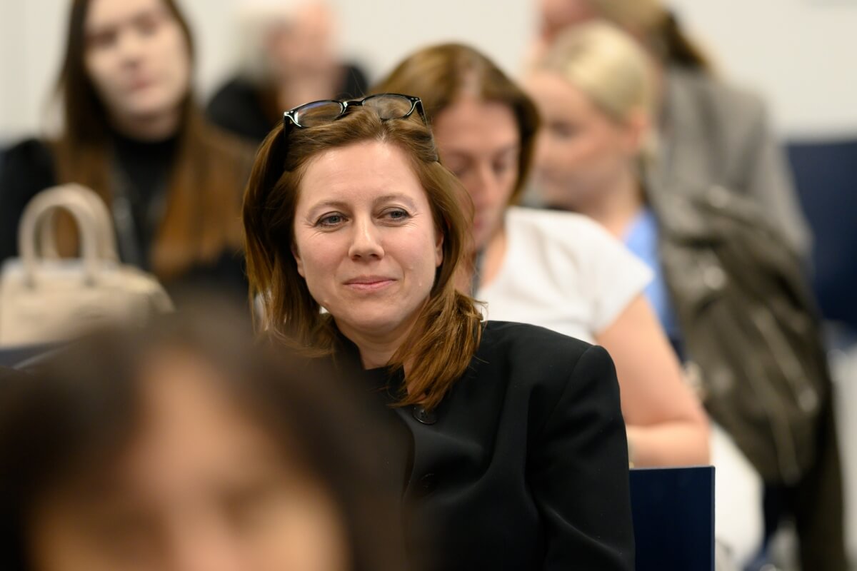 Zbliżenie na kobietę, która siedzi wśród publiczności konferencji naukowej „Innowacje społeczne. Wyzwania – Rozwiązania – Praktyki”, odbywającej się na Uniwersytecie SWPS w Warszawie