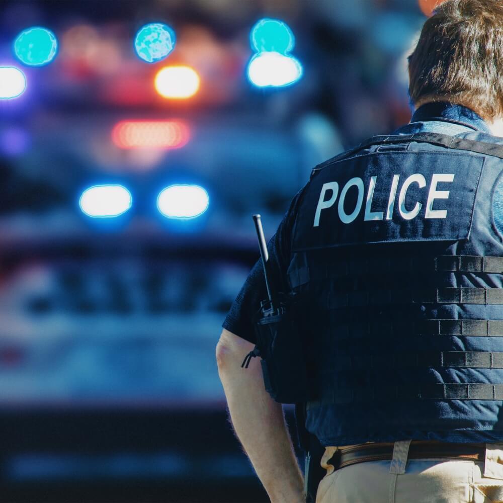 Zdjęcie policjanta tyłem na tle radiowozu